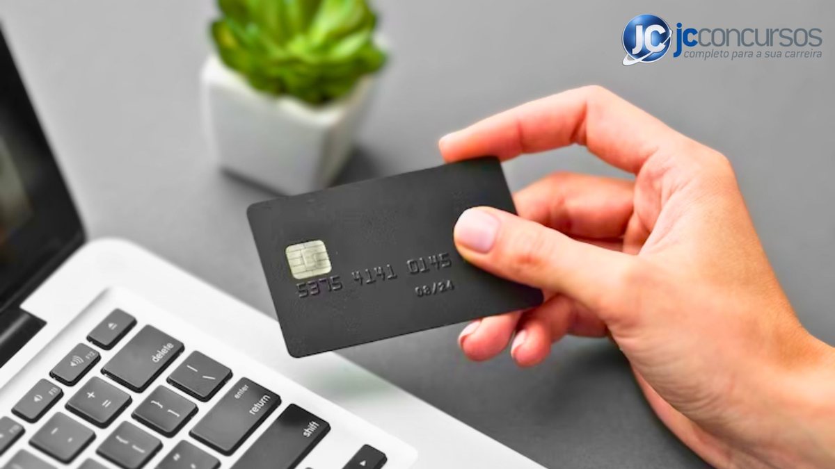 Homem segura cartão de crédito - Divulgação JC Concursos