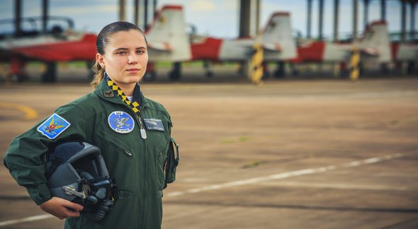 Concurso Aeronáutica: aviadora da Força Aérea Brasileira posa para foto com aeronaves ao fundo - Divulgação