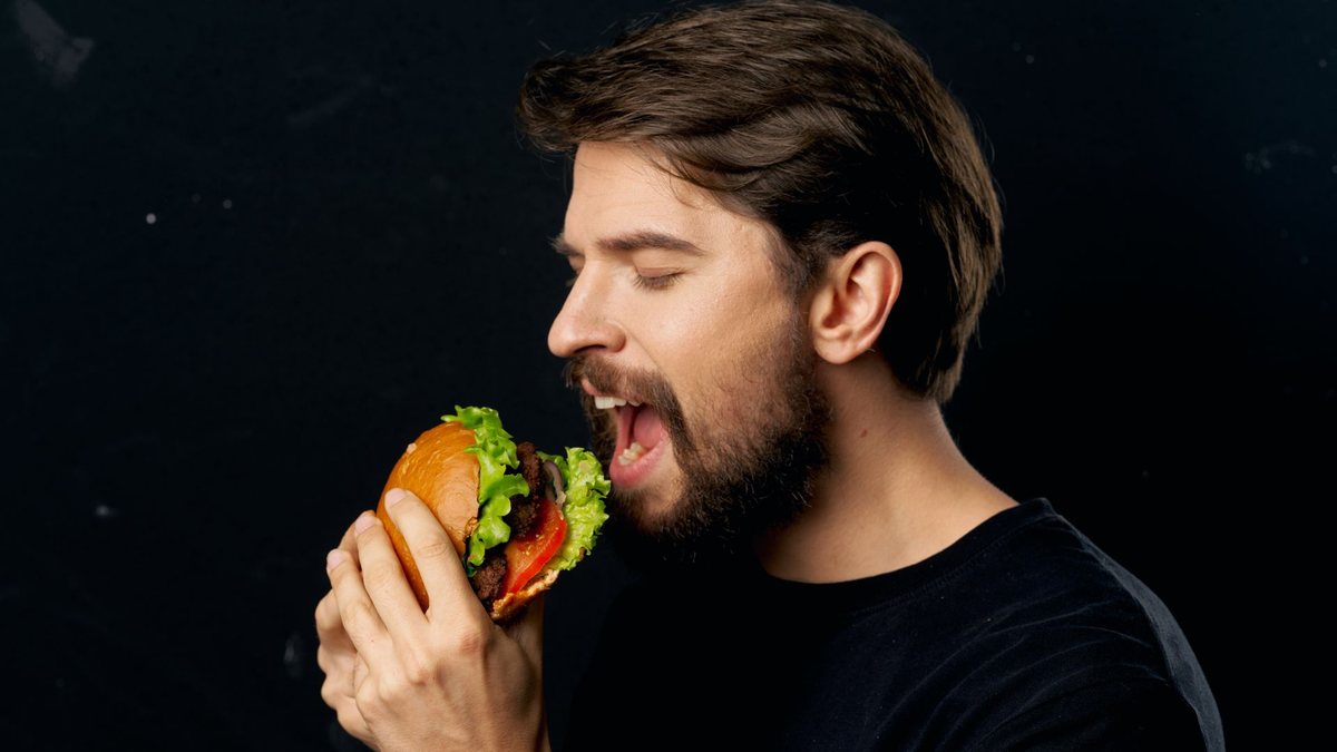Homem leva hambúrguer à boca