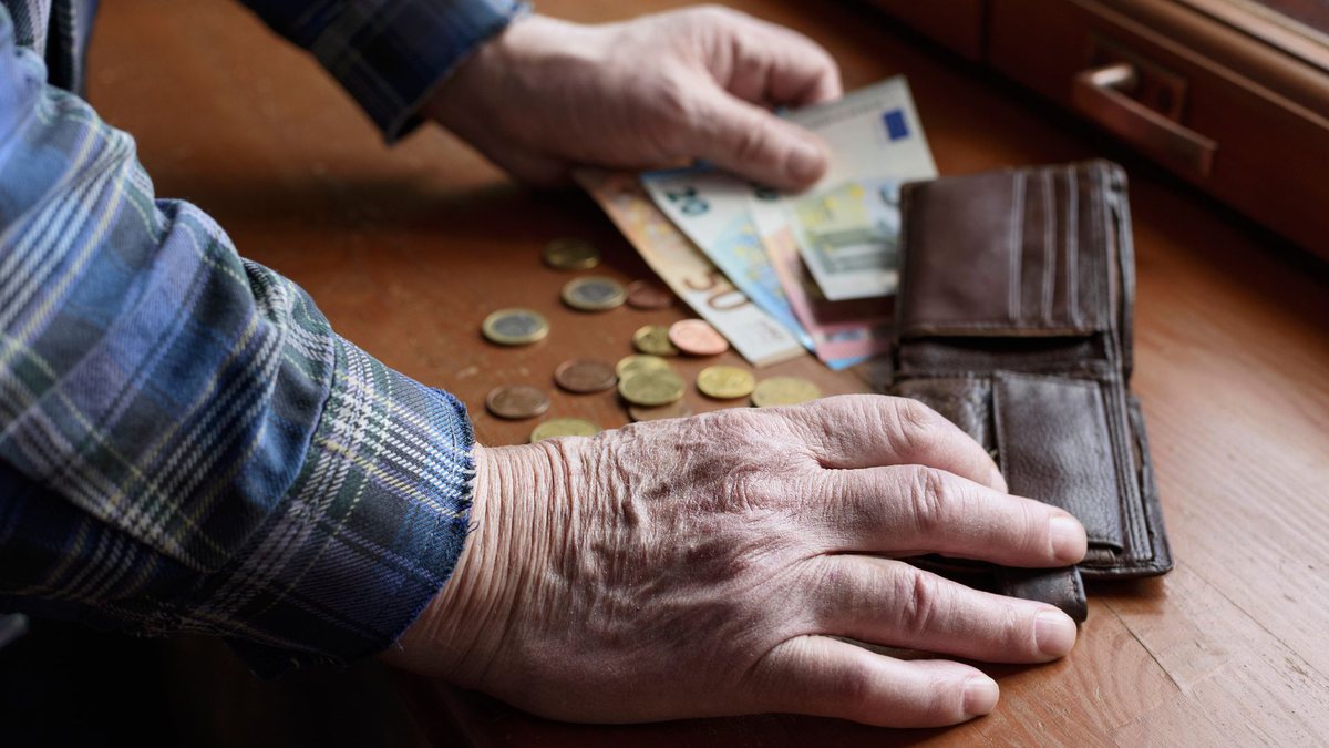 Um idoso segura notas de dinheiro