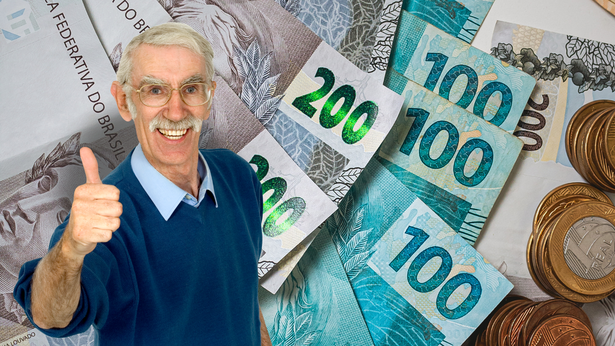 Homem idoso sorri e faz sinal de joia com notas e moedas de reais ao fundo