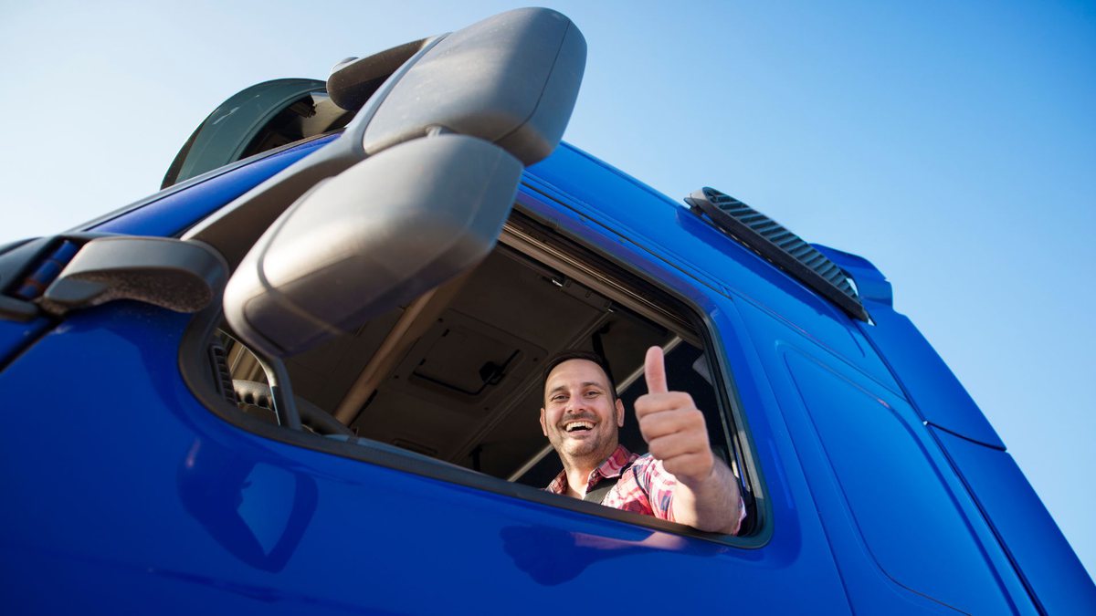 Auxílio caminhoneiro: motorista de caminhão azul faz sinal de positivo com a mão