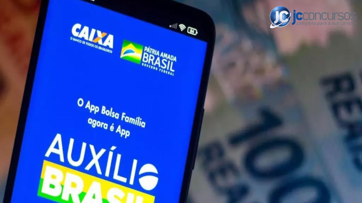 Um celular aberto com o programa do Auxílio Brasil ao lado de notas de dinheiro - Pixabay - Auxílio Brasil terá novo nome no governo Lula