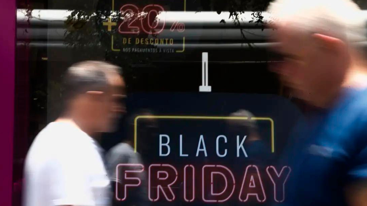 Pessoas passam por vitrine com promoção da Black Friday