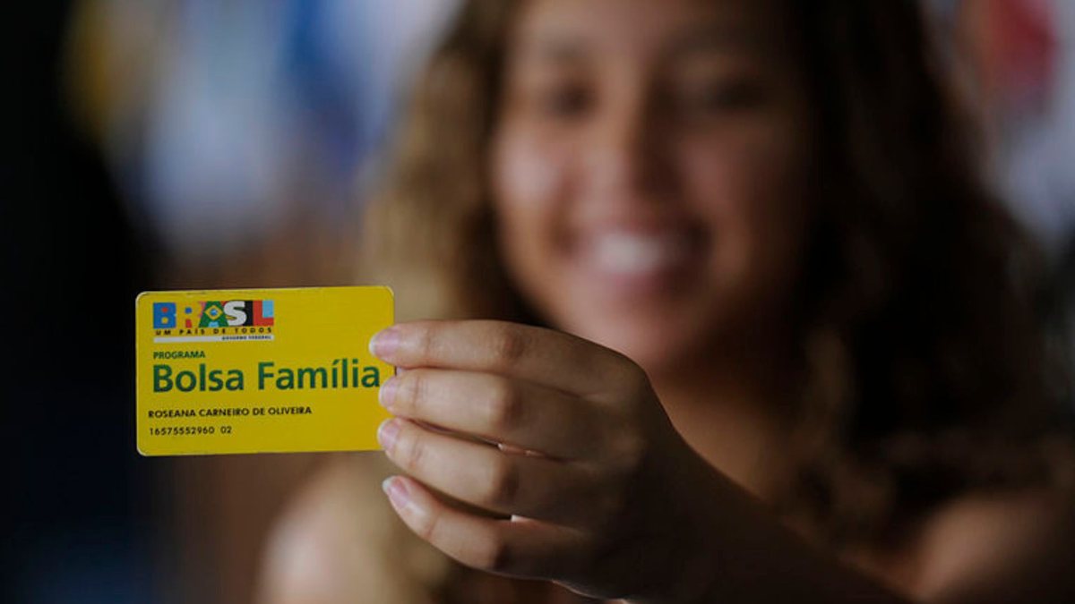 Mulher segura cartão do Bolsa Família