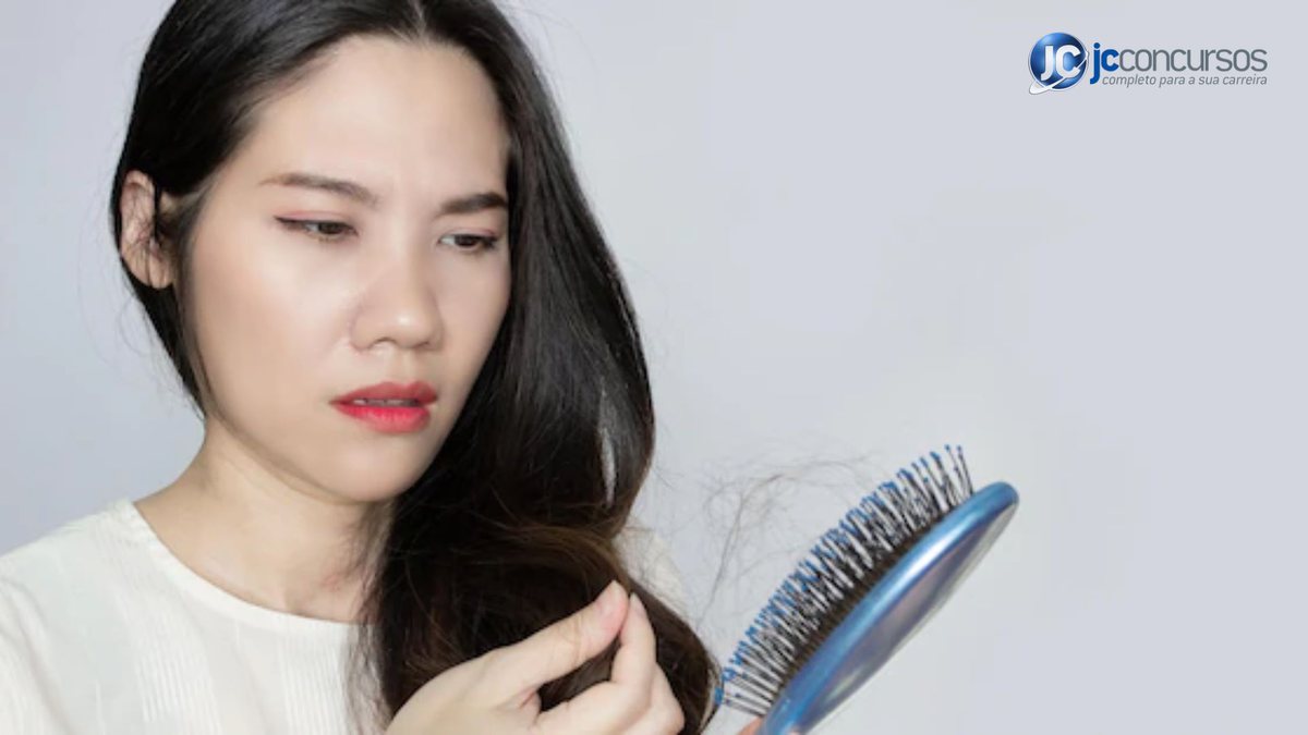 Mulher olha para escova com fios de cabelo - Freepik