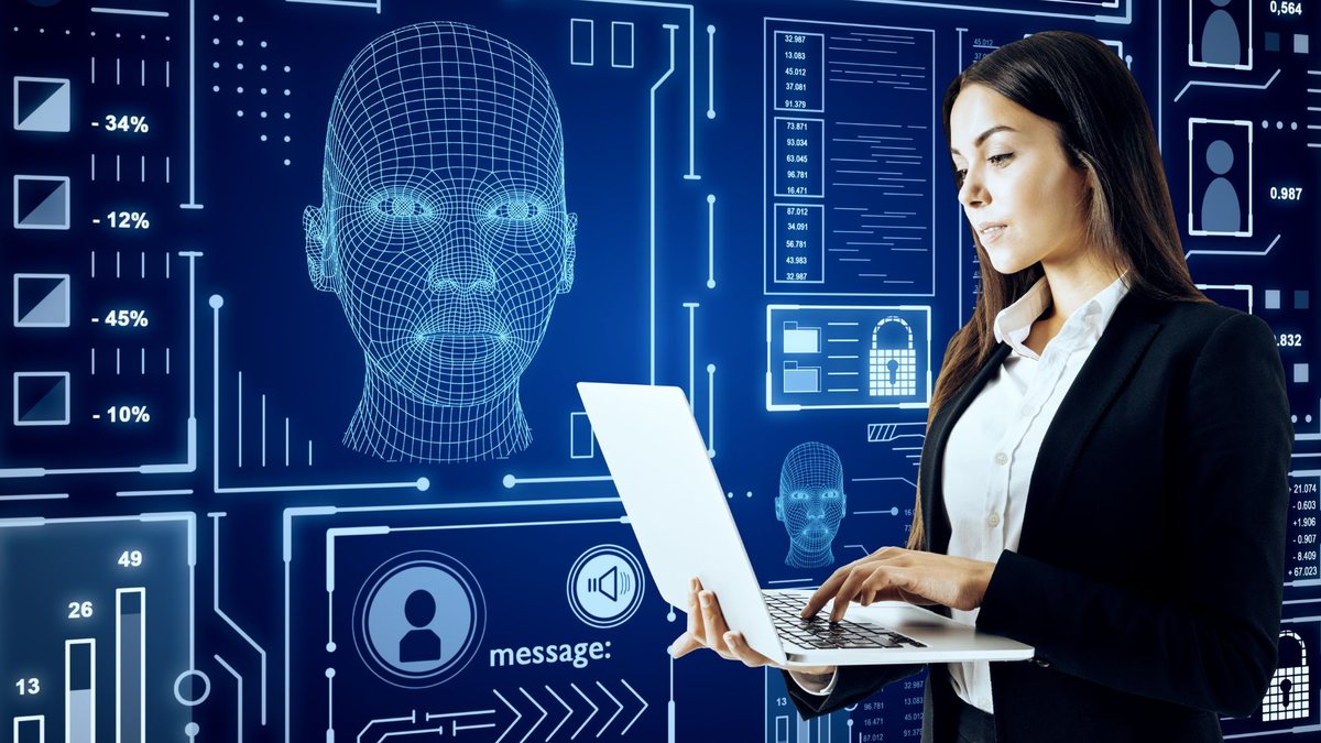 Mulher usa notebook e inteligência artificial aparece em painel eletrônico ao fundo