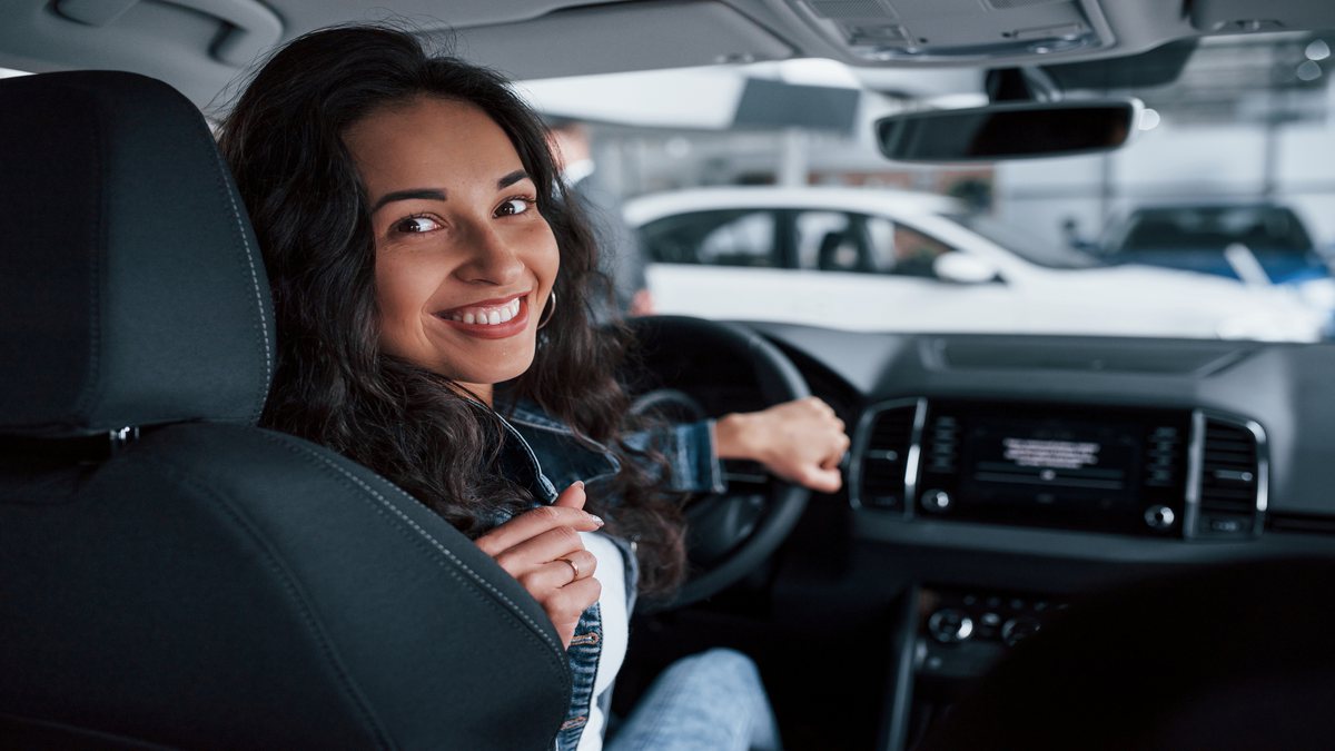 Redução do IPI: mulher sorri enquanto está na condução de automóvel