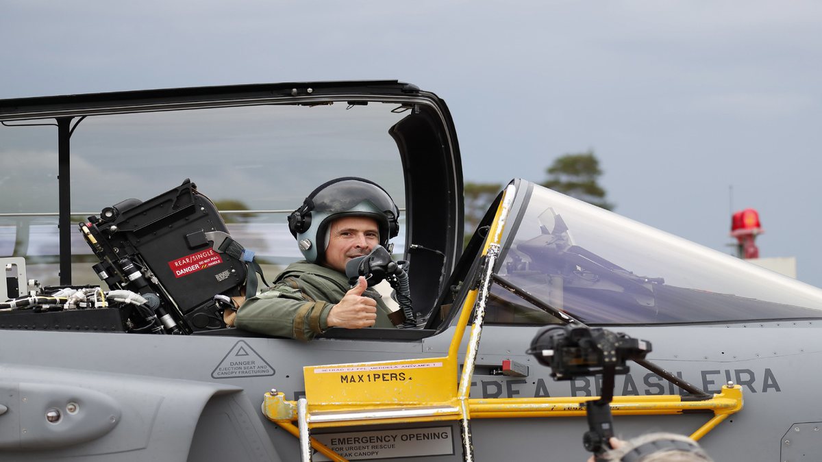 Concurso Aeronáutica: sentado na cabine de aeronave, piloto faz sinal de positivo com a mão