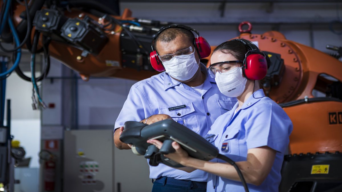 Concurso Aeronáutica: engenheiros observam equipamento eletrônico