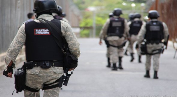 Concurso Depen MG: policiais penais aparecem de costas caminhando em unidade prisional - Divulgação