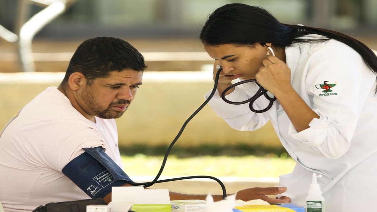 Concurso INCS: profissional de enfermagem afere pressão arterial de homem