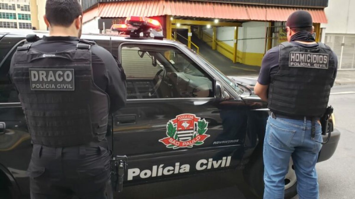 Concurso PC SP: agentes em pé próximos à viatura da Polícia Civil de São Paulo