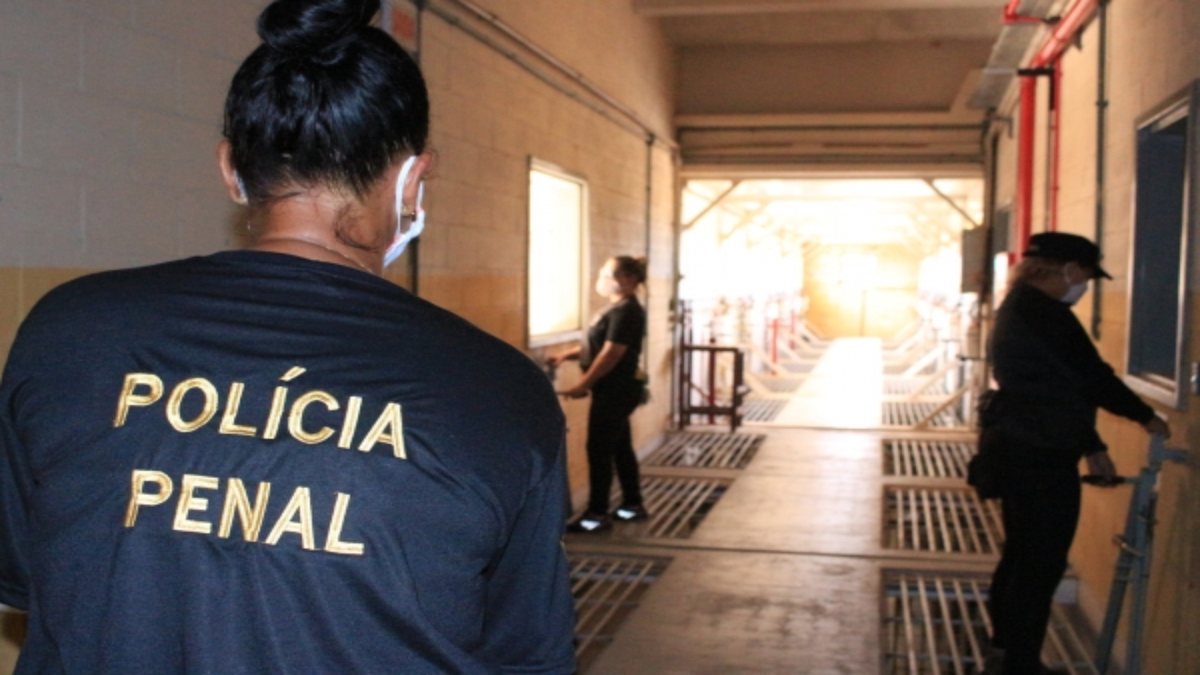Concurso Polícia Penal AL: policial penal caminha em corredor de unidade prisional