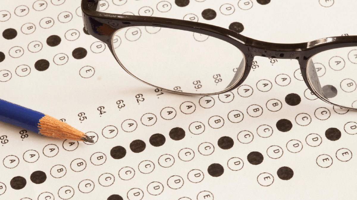 Óculos e lápis em cima de folha de resposta de concurso público