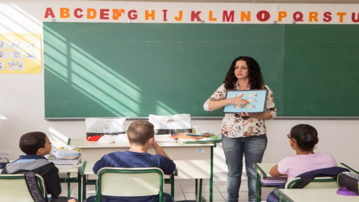 Concurso da Prefeitura de Ouro Verde: estudantes observam explicação de professora em sala de aula