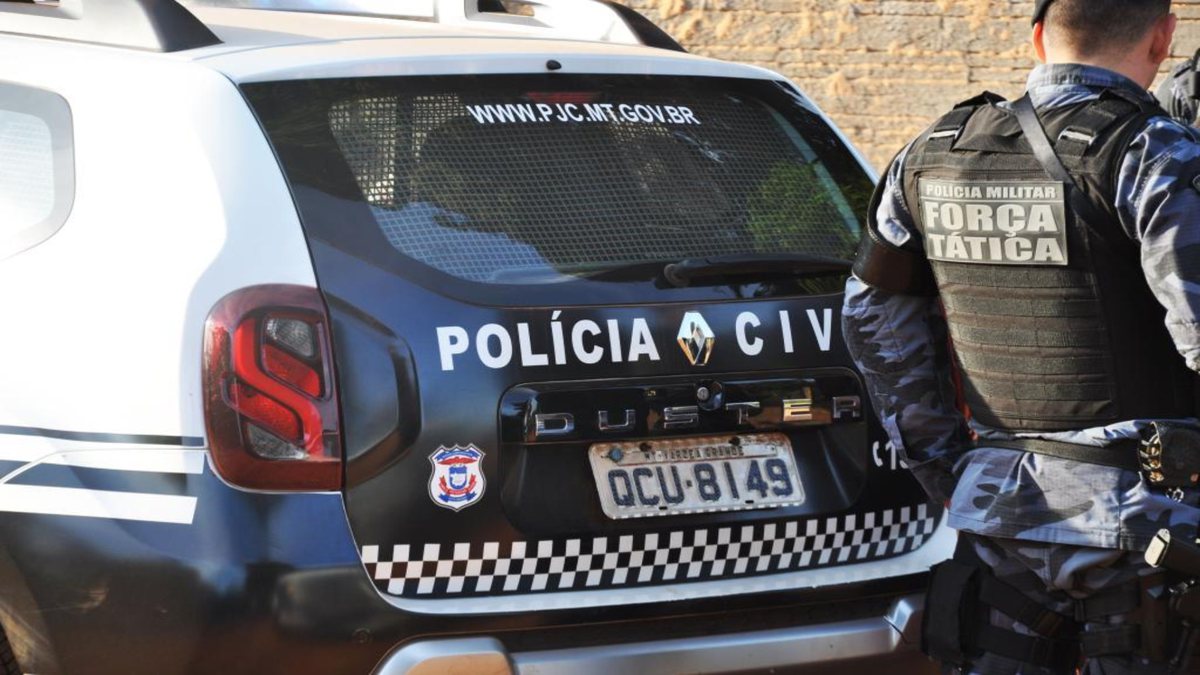 Soldado da Polícia Militar de Mato Grosso ao lado de viatura