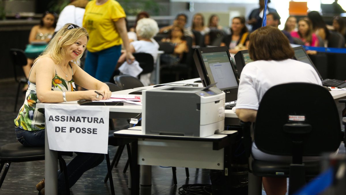 Concursos públicos: mulher assina documento de posse em cargo após aprovação