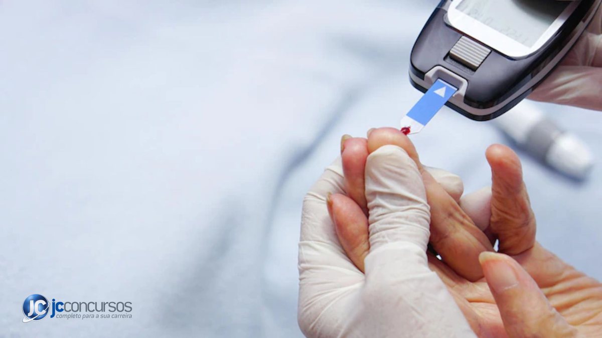 Profissional de saúde colhendo sangue com medidor glicêmico no dedo da paciente - Freepik