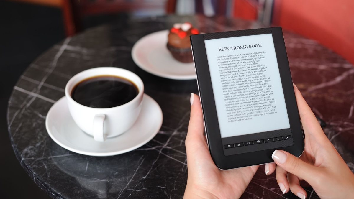 Ebook grátis: mulher lê livro digital enquanto toma café