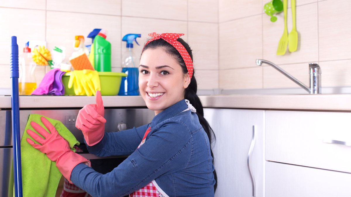 Empregada doméstica com luva de limpeza na cor rosa faz sinal de joia com mão e sorri