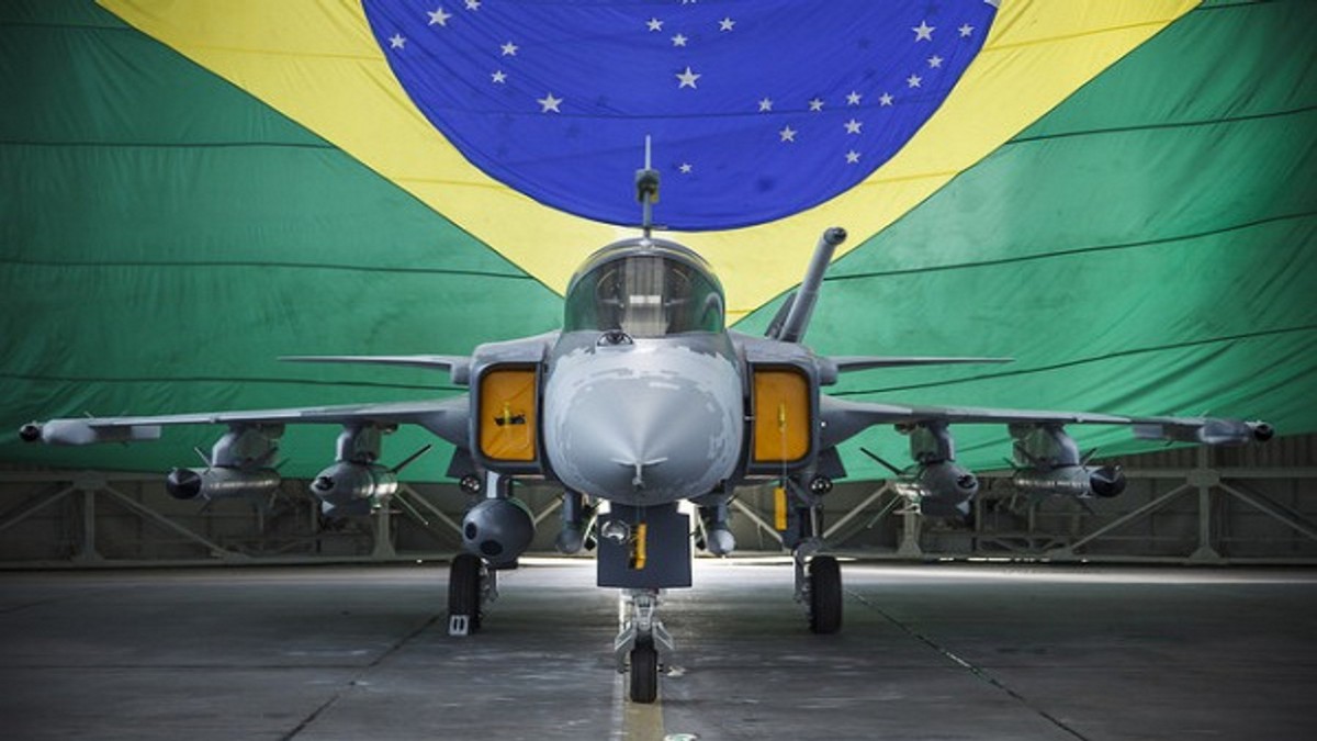 Aeronave da Força Aérea Brasileira estacionada em hangar com bandeira do Brasil ao fundo