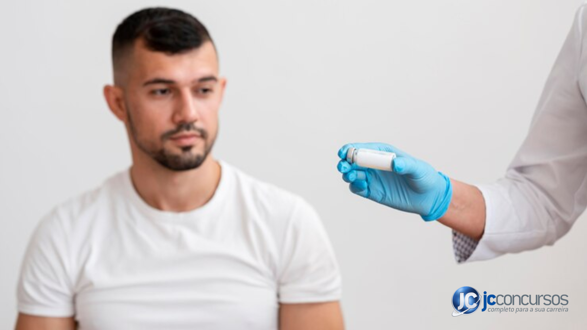 Profissional da saúde segurando ampola para injeção enquanto homem olha para sua mão - Freepik
