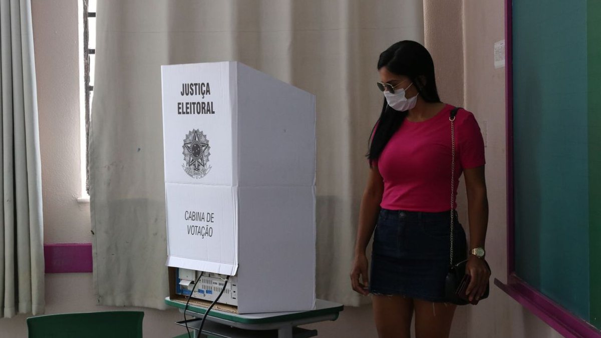 Uma mulher de frente a uma cabine de votação