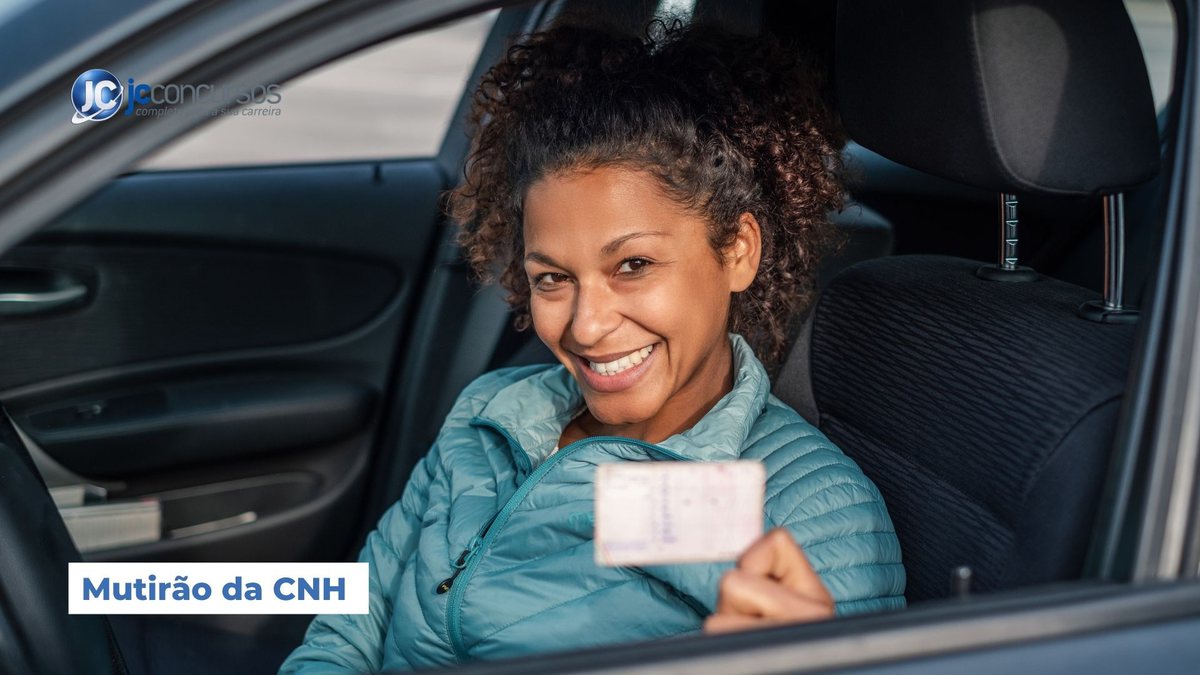Uma mulher dentro de um carro segura documento