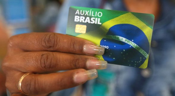 Mulher segura o novo cartão do Auxílio Brasil, com chip - Divulgação/Min.Cidadania