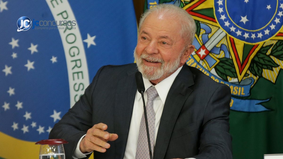 Presidente Lula sorri com bandeira do Brasil ao fundo