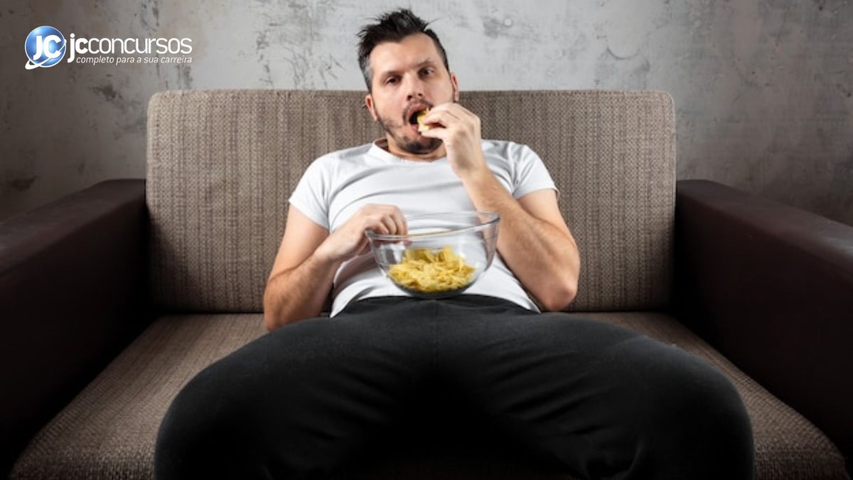 Homem sentado no sofá comendo lanche - Freepik
