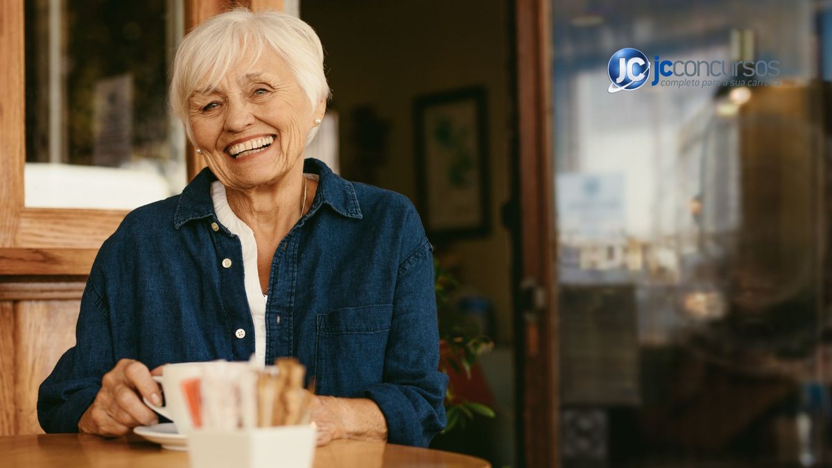 Uma idosa sorri enquanto segura uma xícara