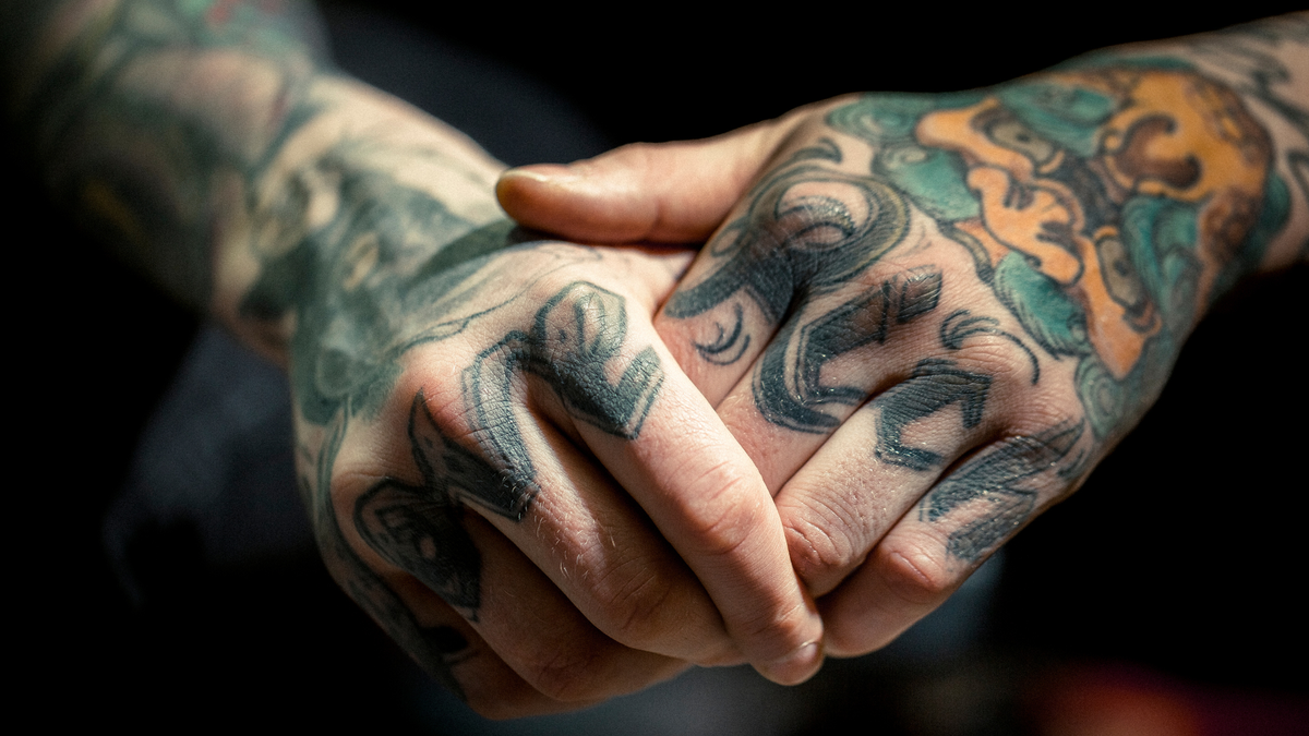 Mãos de homem com várias tatuagens