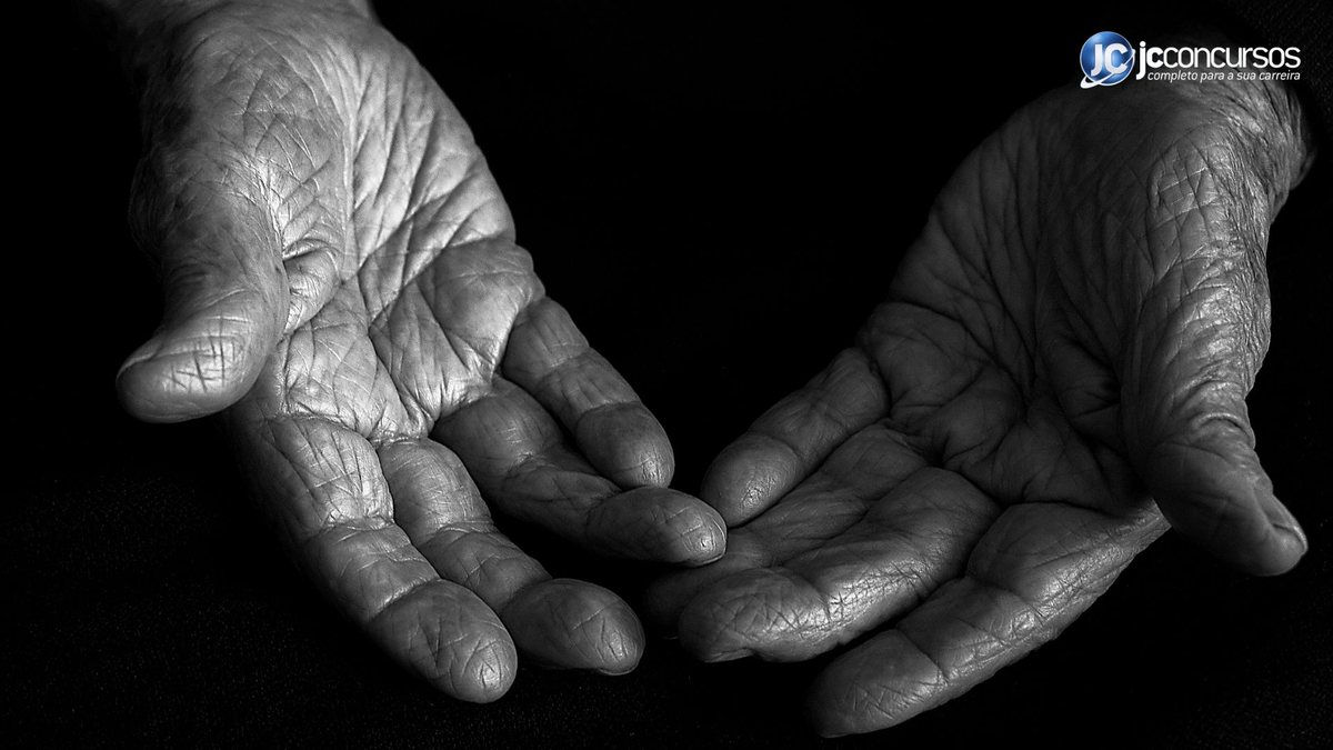 Pessoa estende as mãos vazias em imagem em preto e branco